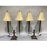 A pair of bronzed effect metal twin light table lamps complete with champagne coloured shades,