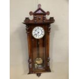 A Victorian walnut wall clock having a white enamel two part dial, black Roman numerals, the