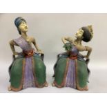 A pair of ceramic figures of female Balinese dancers in pose, coloured in purple, green, red and