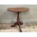 A walnut tripod table of oval outline on a turned pedestal and three downswept legs with scroll feet