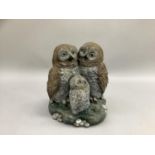 A garden cast concrete ornament in the form of two owls and owlet coloured, 32cm high.