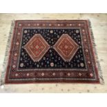 A Middle Eastern rug, the dark blue ground having fox red medallions of diamond shape within