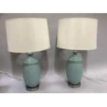 A pair of duck egg blue pottery table lamps of moulded diamond form, with cream drum shades