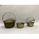 Two brass preserve pans with hoop handles and a brass saucepan