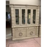 A cream wood effect and glazed four door display cabinet