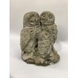 A garden cast concrete ornament in the form of two owls and owlet, 32cm high.