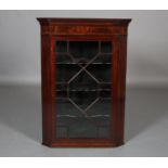 AN EARLY 19TH CENTURY MAHOGANY AND GLAZED CORNER CUPBOARD inlaid in boxwood and ebony chequered