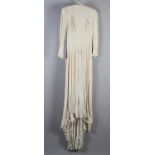 A cream crepe 1940’s wedding dress with train, long sleeves, shoulder pads, and rusched detail to