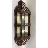 A Victorian mahogany and bevelled mirror lined hanging corner shelf with pierced aprons and angled