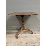 A 19th century mahogany snap top table of rectangular outline on turned column and with tripod base,
