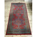 A Turkish rug the red ground with all over stylised design in blue, green and coral, 272cm x 131cm
