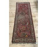 A Middle Eastern rug the red field filled with stylised flowers within an ivory border, 271cm x 95cm