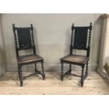 A pair of dark oak hall chairs with panel backs flanked by barley twist uprights, full seat and on