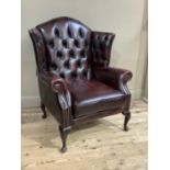 AN ox blood leather and close nailed button upholstered winged armchair