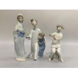 Three Lladro figures, a girl wearing a shawl carrying lilies 24cm, two children in nightwear holding