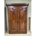 A Victorian mahogany crossbanded two drawer wardrobe having a moulded and foliate carved cornice
