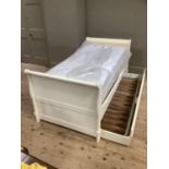 A cream finished continental style bedstead with the panelled ends of serpentine outline, complete