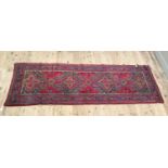A Turkish style rug the red ground filled with geometric motifs in green, blue and pink within