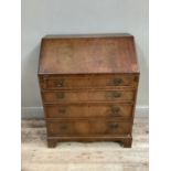 A reproduction walnut veneered bureau with fall front over four long graduated drawers, on bracket