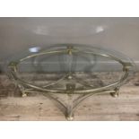 A bevel glass top coffee table raised on three brass and glass column legs joined by curved