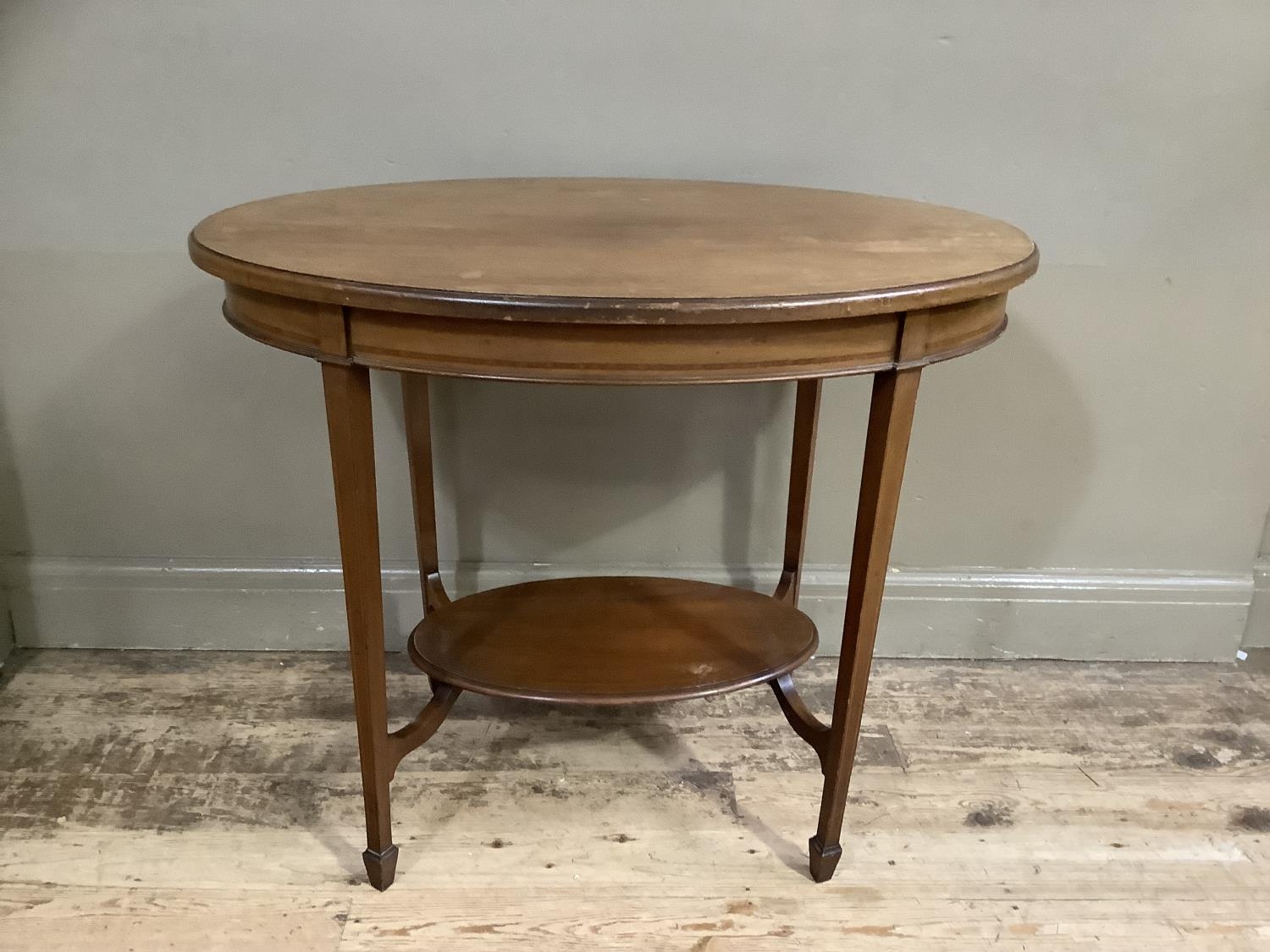 An Edwardian mahogany window table of oval outline on square tapered legs joined by an under tier