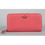 A Kate Spade twelve card zip round wallet in coral pink grained leather, condition: excellent,