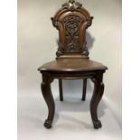 A 19th century mahogany hall chair having a foliate cresting and carved back on cabriole legs