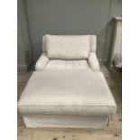 An outsized chair with elongated seat upholstered in oatmeal with upholstered cushion and