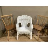 A white wicker armchair together with a pair of Ercol rail back single chairs