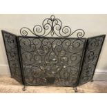 A wrought iron three fold fire screen, the mesh panels overlaid with scrolls and leafage in gilt