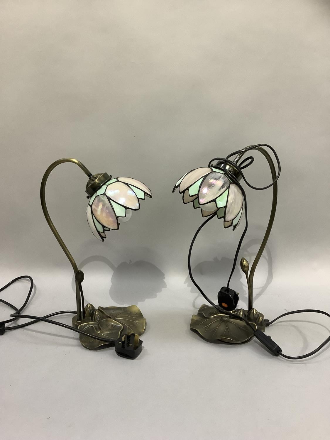 A pair of Tiffany style table lamps with lustre and pale green petal shaped shades on a lily pad