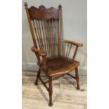 An American oak spindle back chair having a leaf scroll panel top rail above slender turned