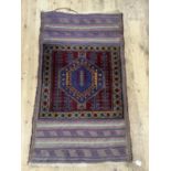 A Middle Eastern rug having a maroon square ground with a mid blue, amber and red medallion within