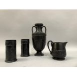 A Wedgwood black basalt two handled urn vase, decorated in low relief with ribboned trophies of