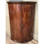 An 18th century mahogany bow front hanging corner cupboard having a moulded cornice above two doors,