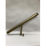 A 19th century brass telescope with folding stand for a tripod and with associated lens, 107cm long