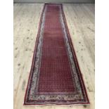 A Middle Eastern runner, the red ground filled with a repeat pattern within a stylised foliate