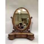 A Victorian mahogany toilet mirror having an oval glass, foliate serpentine upright, the base with