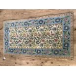 A wool woven rug, the ivory field with a profusion of trailing flowers within a pale blue border