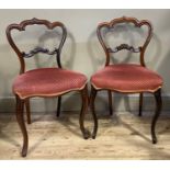 A pair of Victorian walnut single chairs having an ogee arch profile, open back with C-scroll tie