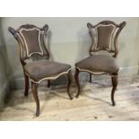 A pair of Victorian walnut salon chairs having an arched and foliate carved cresting rail above an