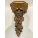 A Victorian oak wall bracket carved as face mask of a King and fruiting branch
