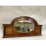 An early 20th century mahogany and satinwood banded mirror back of semi arched outline with bevelled