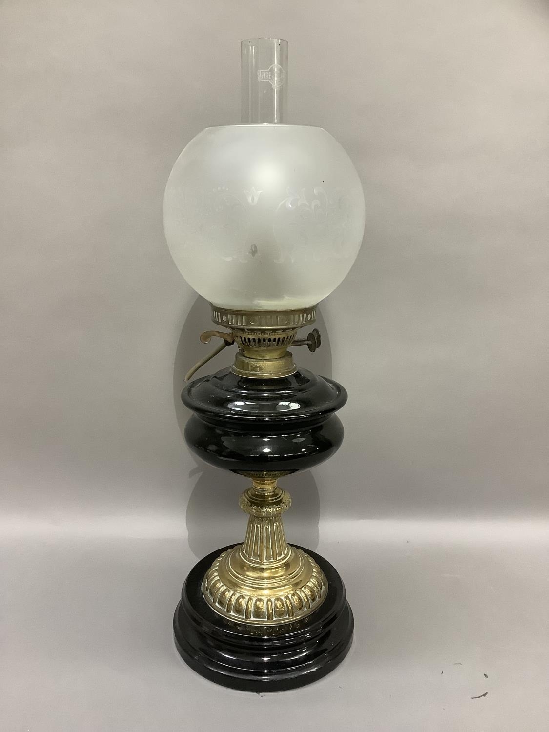 A Victorian black glass and brass oil lamp with opaque etched shade