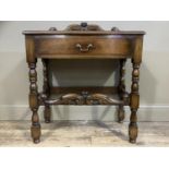 An oak side table having a foliate carved short back, frieze drawer and on turned and square framing