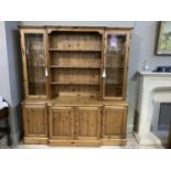 A pine breakfront dresser having open shelves to the centre flanked by glazed cupboard to either