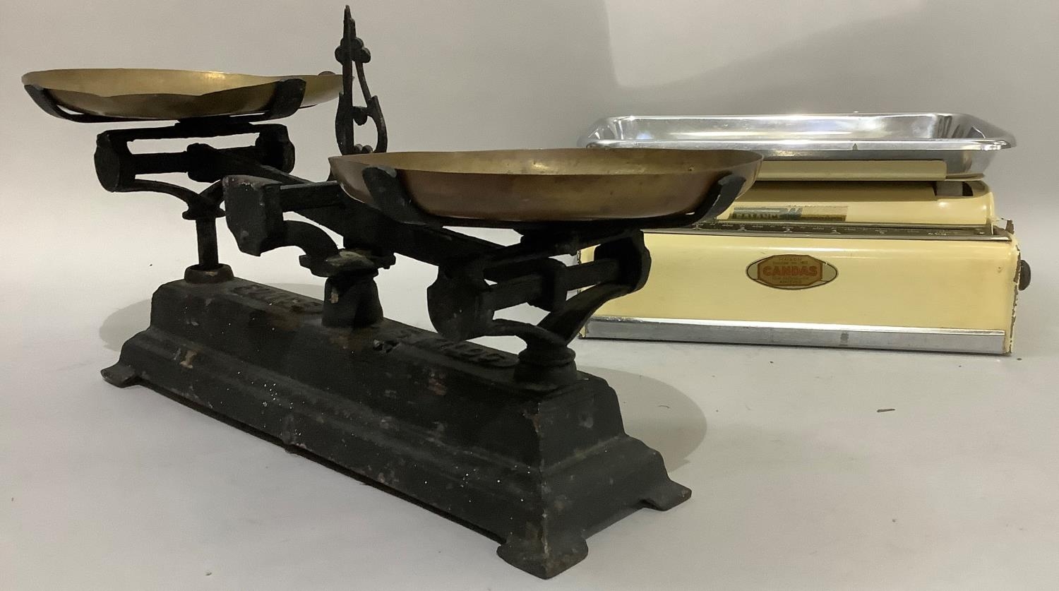 A set of iron weighing scales with brass pans and another pair of weighing scales in cream enamel