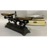 A set of iron weighing scales with brass pans and another pair of weighing scales in cream enamel