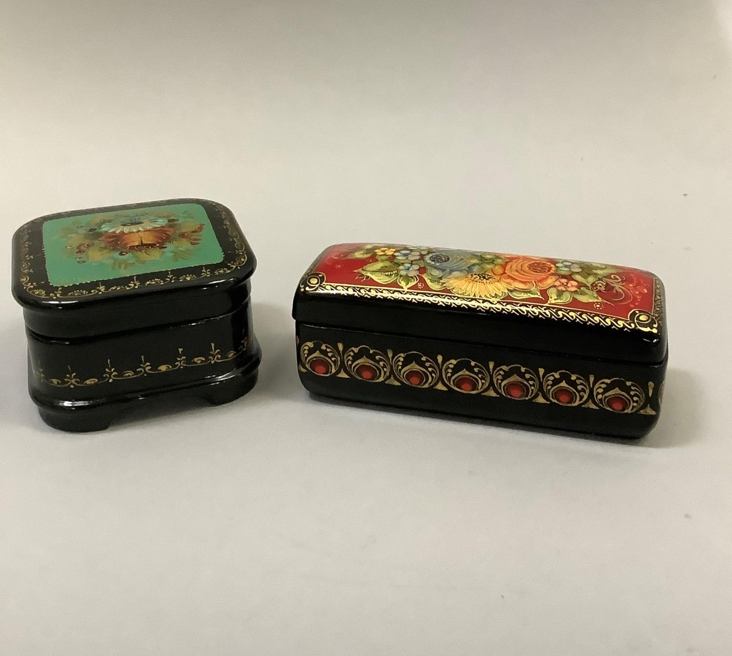 Two hand painted Russian black lacquered boxes of square outline painted with flowers to the lid and