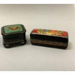 Two hand painted Russian black lacquered boxes of square outline painted with flowers to the lid and